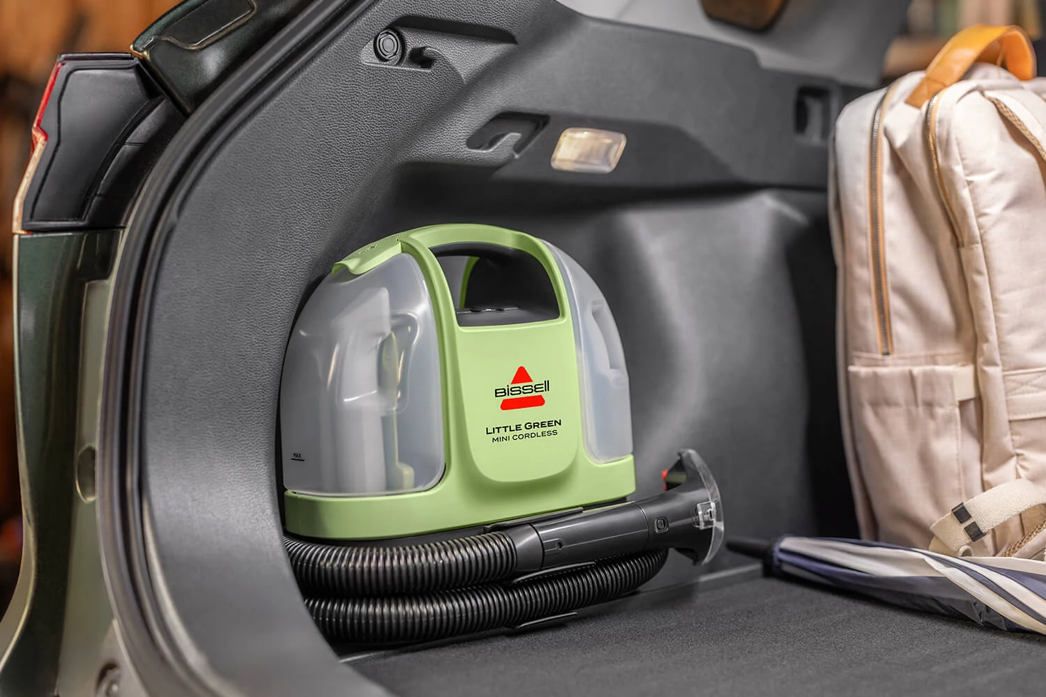 BISSELL Little Green Mini Cordless 4015 manufacturer image, shown stored in a vehicle cargo area